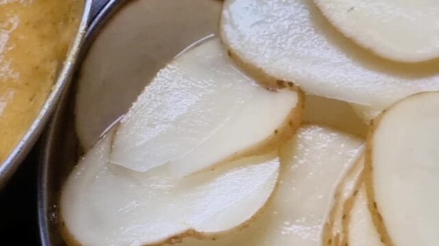 thinly sliced raw potatoes, which are indeed likely being prepared for making potato chips or crisps, as well as a bowl containing a batter of gram flour, possibly for coating these potato slices