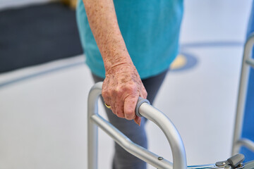 Senior hand on walker handle in rehabilitation center environment