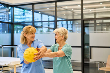 Elderly woman assisted by therapist during rehabilitation therapy at medical facility