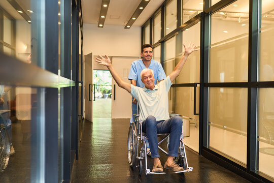 Friendly caregiver assisting a wheelchair user in a rehabilitation facility hallway