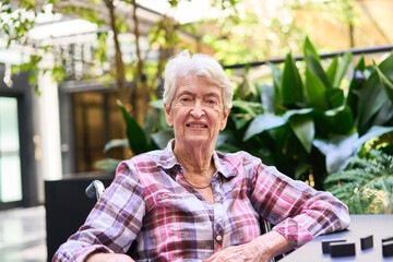 Smiling elderly woman enjoying time outdoors in a rehabilitation facility garden
