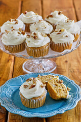 pumpkin cupcakes topped with vanilla frosting and chopped nuts
