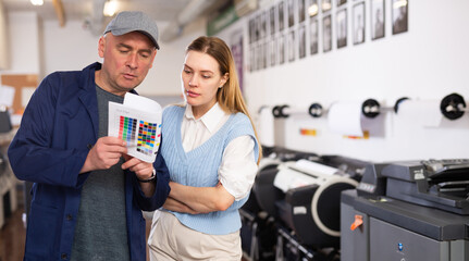 Man and woman printing office workers discussing usage of test page for printer.