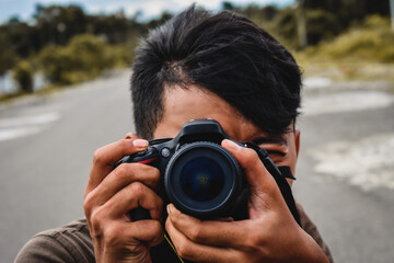 Obraz premium Man Taking Photo Outdoors with DSLR Camera
