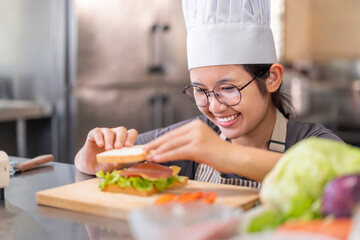 Smiling Young Female Chef Preparing a Sandwich in a Professional Kitchen
