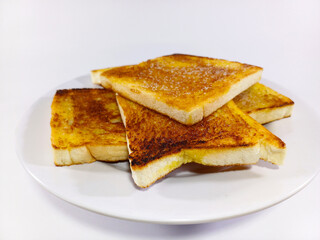 A pile of evenly toasted, golden-brown bread slices, buttered and sugared, on a white plate, against a white background. Related to breakfast food, sweet snacks, comfort food, culinary delights
