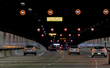 View from a car, Sydney toll road tunnel showing speed signs and four lanes with camera shake
