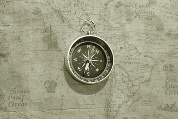 Classic round compass on background of old vintage map of world