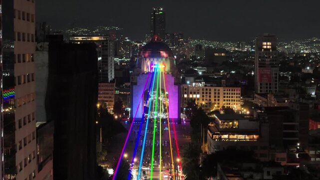 backwards drone shot of pride colors laser light in mexico city revolution monument