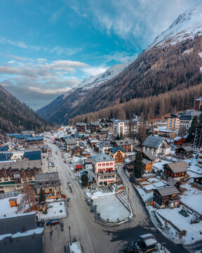 Aerial view of the snow-dusted village nestled amidst towering, snow-capped mountains, a serene tableau of winter's embrace, Zinal, Valais, Switzerland.