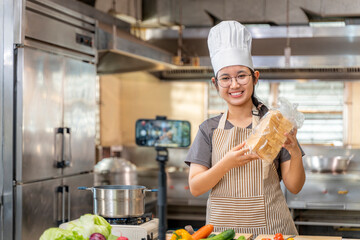 Title: Young Asian Female Chef Vlogging with Bread in Kitchen