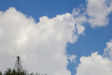 High-voltage tower against the blue sky with white clouds. natural background