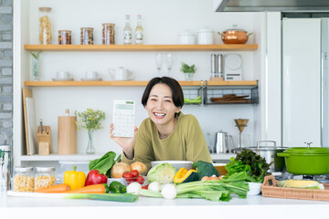 キッチンで電卓を持つミドルの女性