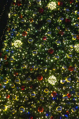 Christmas tree decorated with colorful baubles and lights at night.