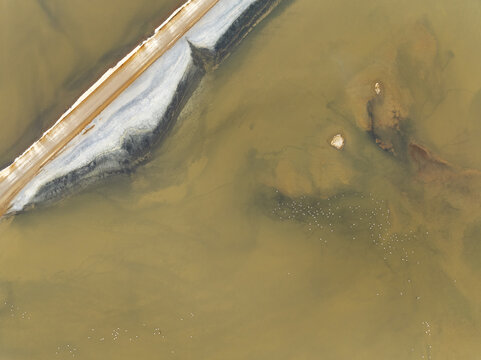 Aerial view of shallow waters meeting the textured shoreline, revealing a blend of earthy tones and striking contrasts, Walvis Bay, Walvis Bay lagoon, Namibia.
