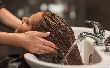 Hair washing session at a salon with a stylist using warm water and gentle techniques on a client's long hair