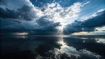 Fototapeta premium Dramatic sunbeams pierce stormy ocean clouds reflected on wet sand