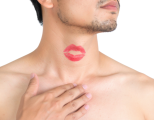 A shirtless man with facial hair has a red lipstick kiss mark on his neck and his hand resting on his chest against a black background.