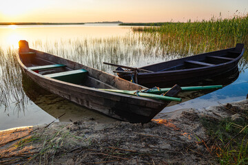 Traditional wooden fishing boat with oars on the lake shore.