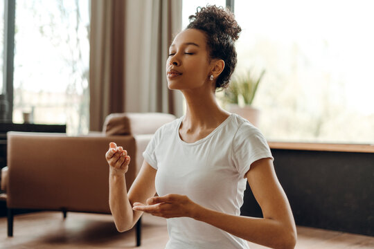 Portrait of beautiful African American woman doing breathing meditation at home - Powered by Adobe
