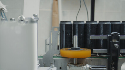 Aluminum cans are moving on a conveyor belt, passing through a labeling machine in a beverage production factory, showcasing the automated process of packaging drinks