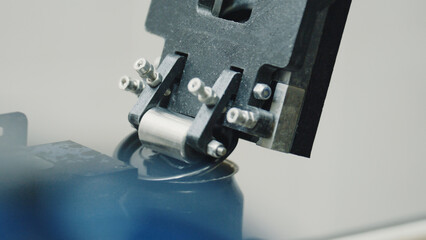 Close up view of a robotic arm skillfully closing the lid of a blue paint can in an industrial factory setting, highlighting advancements in automation within the manufacturing process