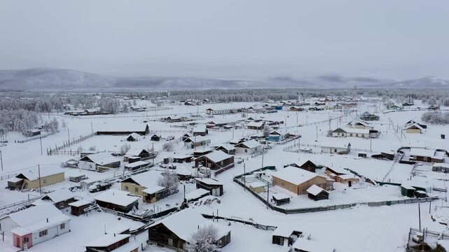 Aerial view of a remote village with snow covered houses amidst a landscape of white and grey, a stark beauty, Oymyakon, Sakha Republic, Russia.