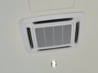 Fototapeta premium Ceiling cassette air conditioner unit providing cooling and comfort. modern HVAC system with ventilation for optimal climate control in an office or home interior environment