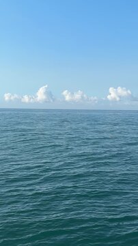 Blue sea waves, clouds and blue sky, vertical video.