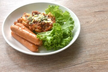 steamed macaroni dressing fried chop pork and slice tomato in ketchup sauce with sausage couple lettuce on plate  