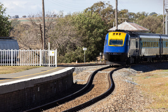 Looking along train tracks to a platform and oncoming XPT train