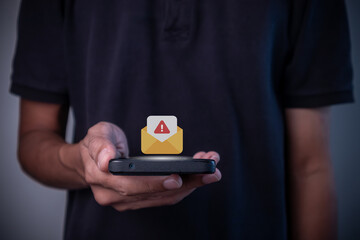 A man holding smartphone with message or email notification with warning symbol