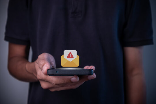 A man holding smartphone with message or email notification with warning symbol