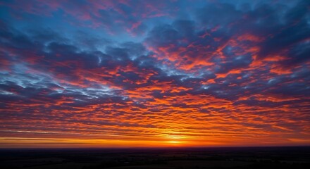 Fototapeta premium Dramatic fiery sunset with vibrant orange and blue colors over a dark horizon