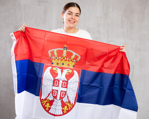 Portrait of positive young woman with the flag of Serbia
