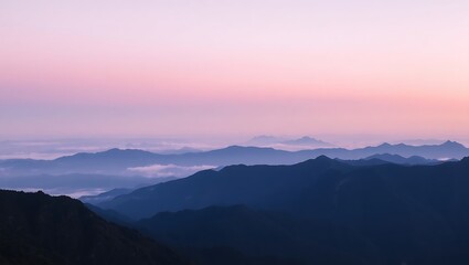 Fototapeta premium A scenic view of layered mountain ranges under a pastel colored sky at dusk or dawn with soft lighting