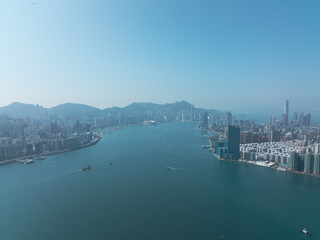 Naklejka premium Aerial view of central Hong Kong, China. Cityscape with skyscrapers lining the harbor under a clear sky. Urban scene showcasing the dense architecture and waterfront.