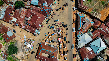 Aerial view of the bustling market street lined with colorful umbrellas and cars amidst the rusty rooftops, Jos, Plateau, Nigeria.