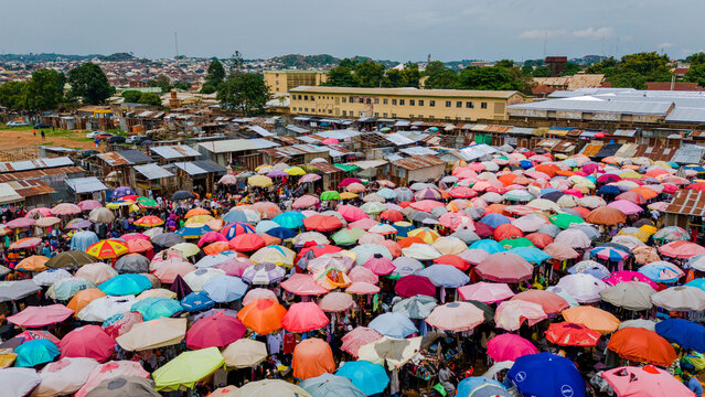 Jos, Nigeria - 28 July 2025: Aerial view of a vibrant marketplace teeming with life, a kaleidoscope of colourful umbrellas shielding vendors and shoppers amidst the city's hustle.