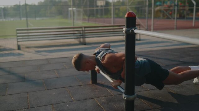 A man is doing an intense exercise routine on parallel bars in an outdoor park setting. The image captures the essence of fitness, determination, and healthy lifestyle in a natural environment.