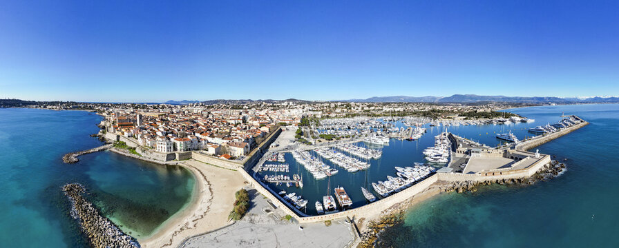 Aerial view of boats clustered in the marina, contrasting against the vibrant cityscape under a clear sky, Antibes, Provence-Alpes-C&Atilde;&acute;te d'Azur, France.