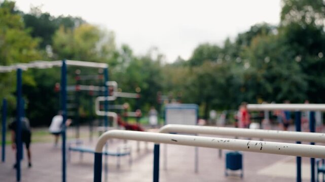 Blurred View of People Exercising in an Outdoor Gym in a Park. Adults Engaging in Various Fitness Activities. Promoting Health, Wellness, and Community Recreation.