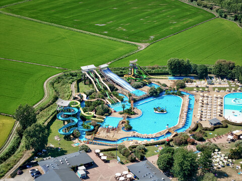 Aerial view of a vibrant water park contrasting against the geometric patterns of surrounding fields, 1 Via Case Sparse, Piemonte, Italy.