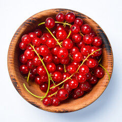Wooden bowl with fresh red currant berries. On a white background, close-up, macro.