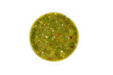 a bowl of green salsa on a white surface