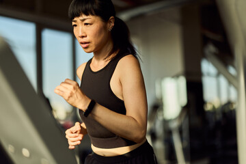 Focused Woman Running on a Treadmill at a Gym for Fitness Training
