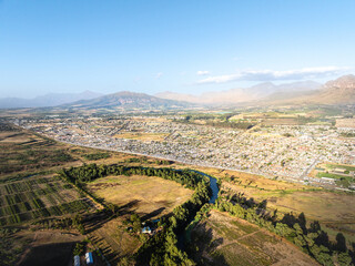 Eine weite Luftaufnahme der Winelands mit Stadtgebieten, Flüssen, Seen und Bergen unter klarem blauem Himmel in Paarl, Südafrika
