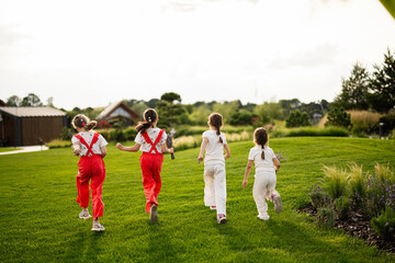 Obraz premium Children running together in a park with grass and trees under sunlight