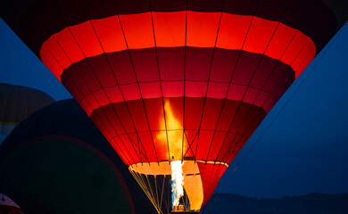 Hot air balloon filling with air using gas burner in dawn light