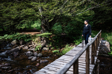 Hiker walking on wooden bridge over mountain river in forest